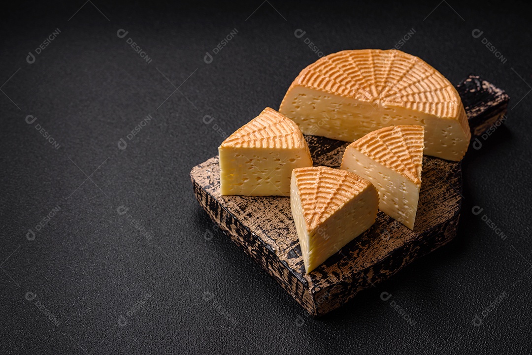 Delicioso queijo artesanal feito de leite de vaca ou cabra sobre um fundo escuro de concreto