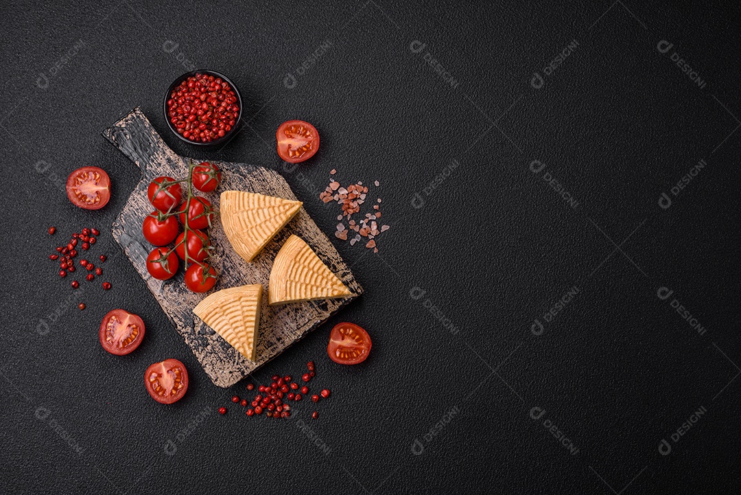 Delicioso queijo artesanal feito de leite de vaca ou cabra sobre um fundo escuro de concreto