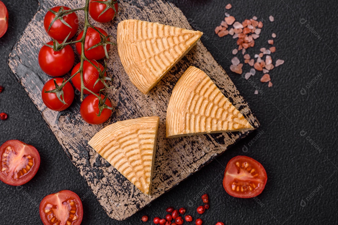 Delicioso queijo artesanal feito de leite de vaca ou cabra sobre um fundo escuro de concreto