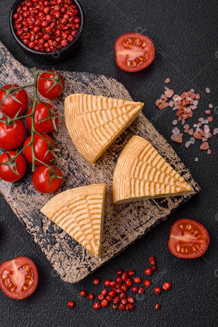 Delicioso queijo artesanal feito de leite de vaca ou cabra sobre um fundo escuro de concreto