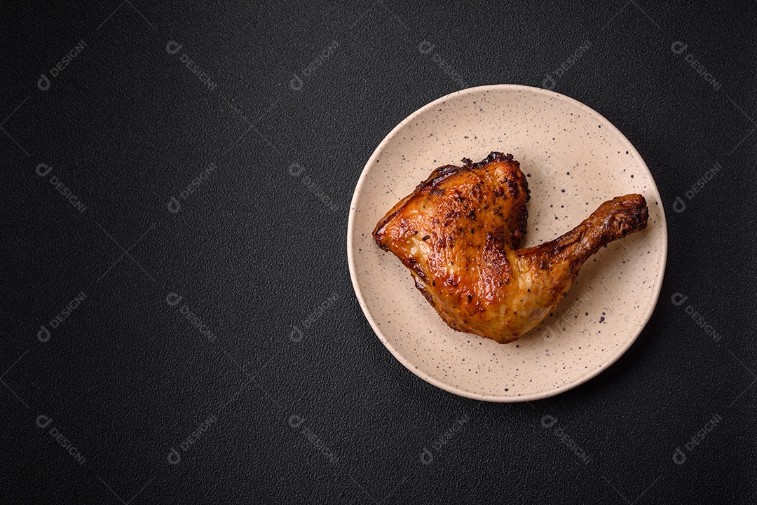 Deliciosa coxa ou quarto de frango grelhado com sal e especiarias em fundo escuro de concreto