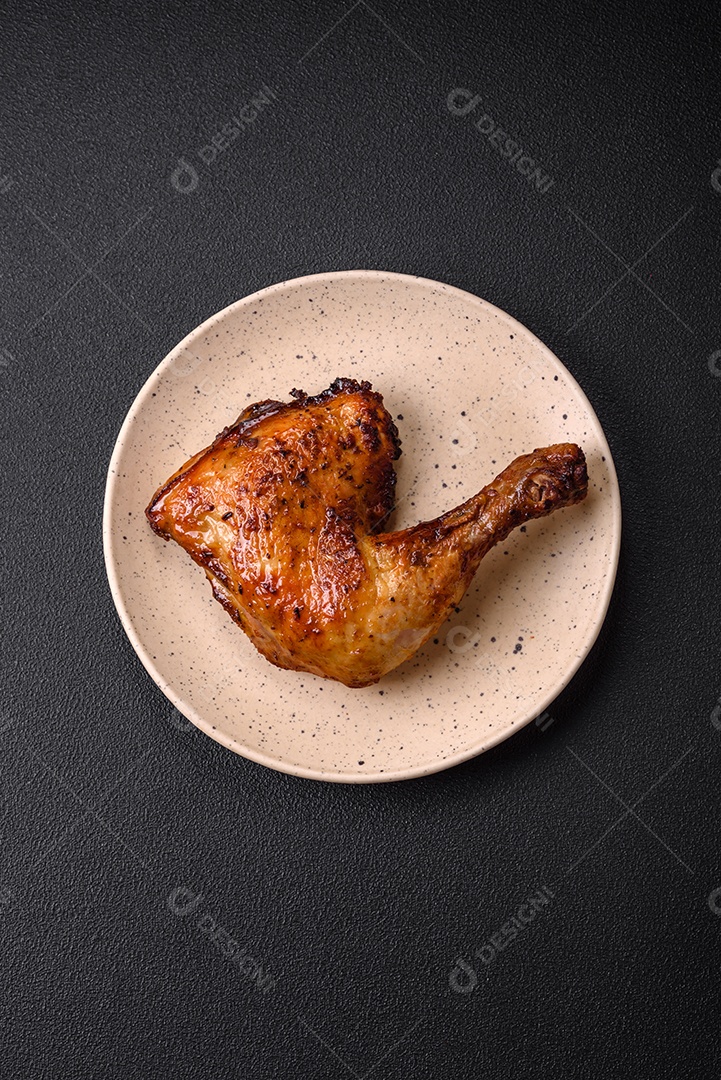 Deliciosa coxa ou quarto de frango grelhado com sal e especiarias em fundo escuro de concreto