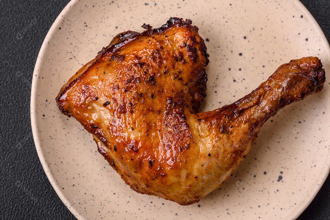 Deliciosa coxa ou quarto de frango grelhado com sal e especiarias em fundo escuro de concreto