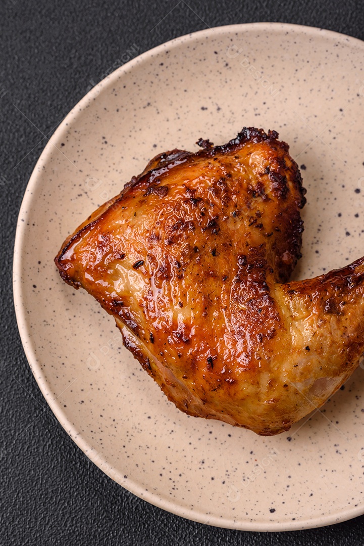 Deliciosa coxa ou quarto de frango grelhado com sal e especiarias em fundo escuro de concreto