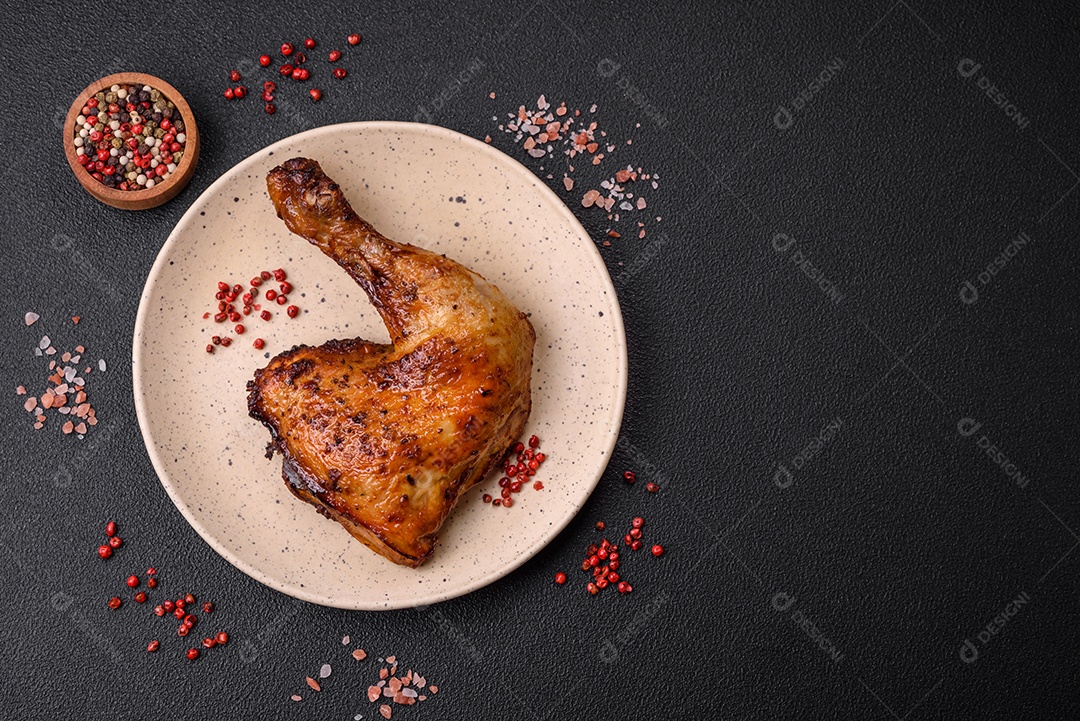 Deliciosa coxa ou quarto de frango grelhado com sal e especiarias em fundo escuro de concreto