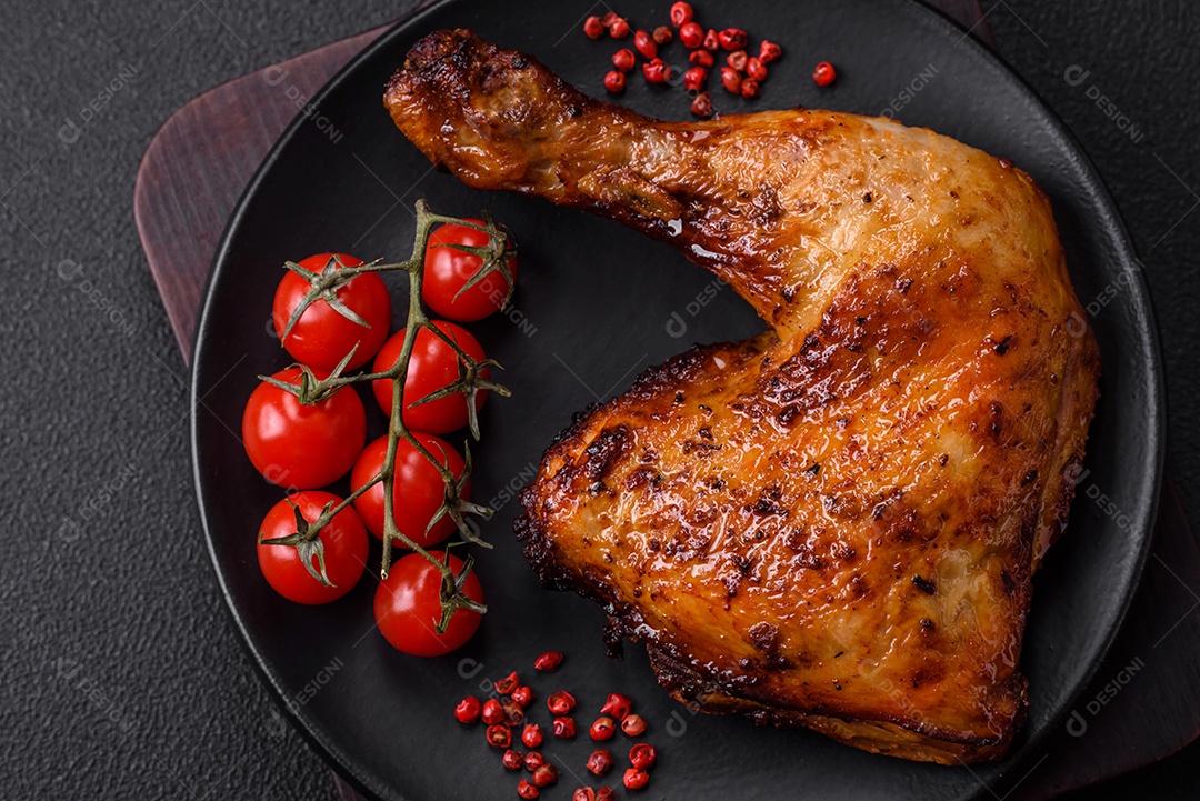 Deliciosa coxa ou quarto de frango grelhado com sal e especiarias em fundo escuro de concreto