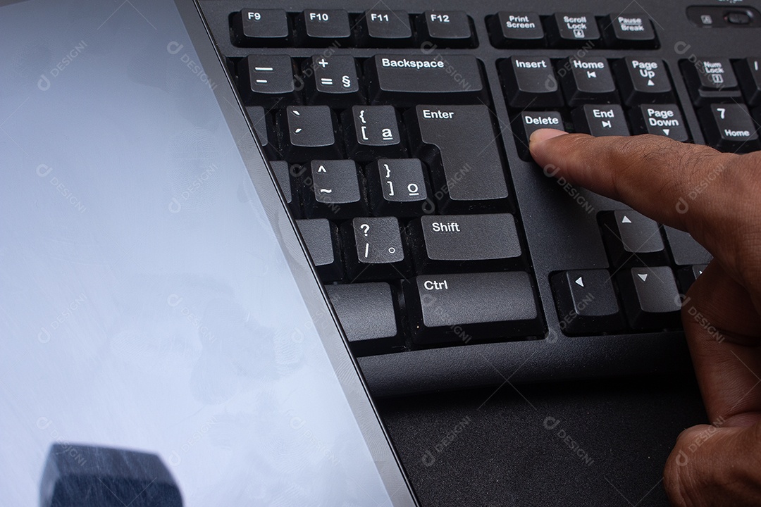 Mão digitando no teclado perto da mesa