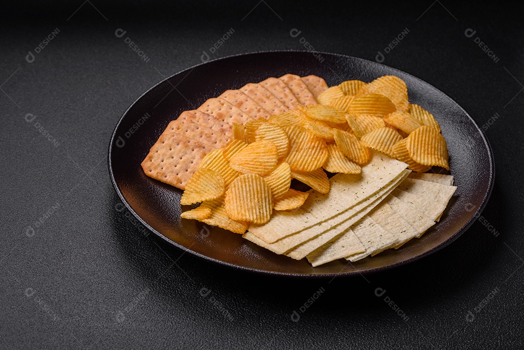 Batatas fritas crocantes com sal, especiarias e ervas sobre um fundo escuro de concreto