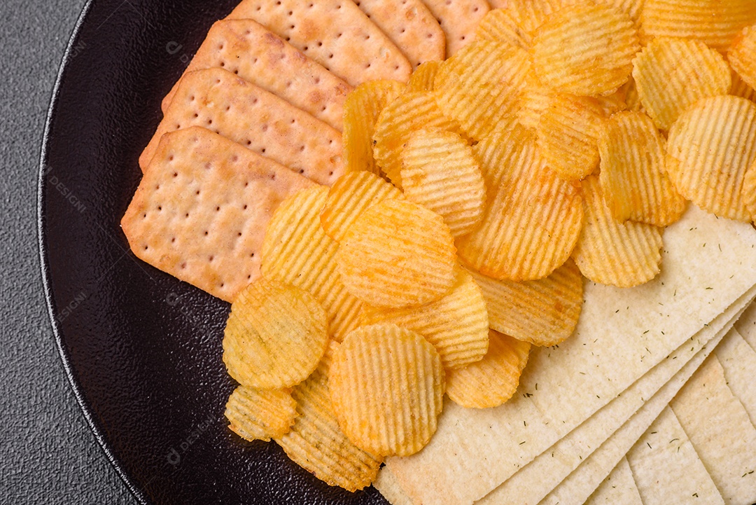 Batatas fritas crocantes com sal, especiarias e ervas sobre um fundo escuro de concreto