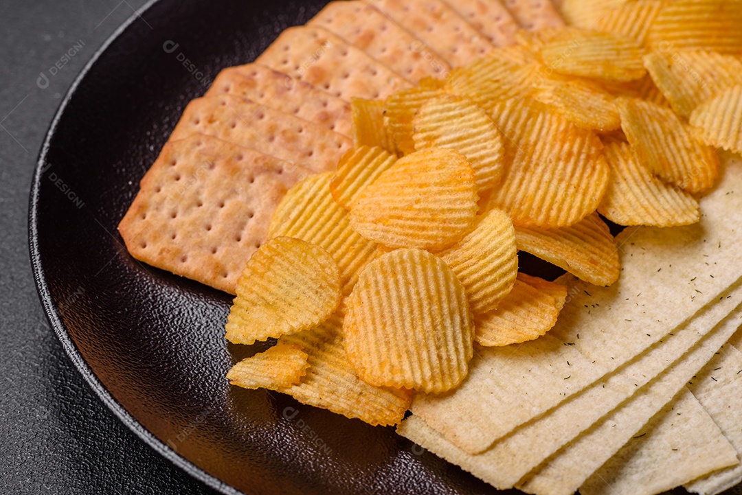 Batatas fritas crocantes com sal, especiarias e ervas sobre um fundo escuro de concreto