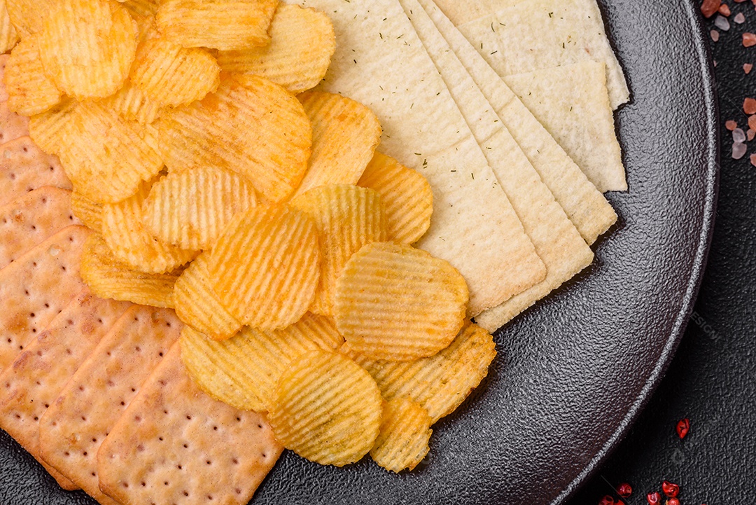 Batatas fritas crocantes com sal, especiarias e ervas sobre um fundo escuro de concreto