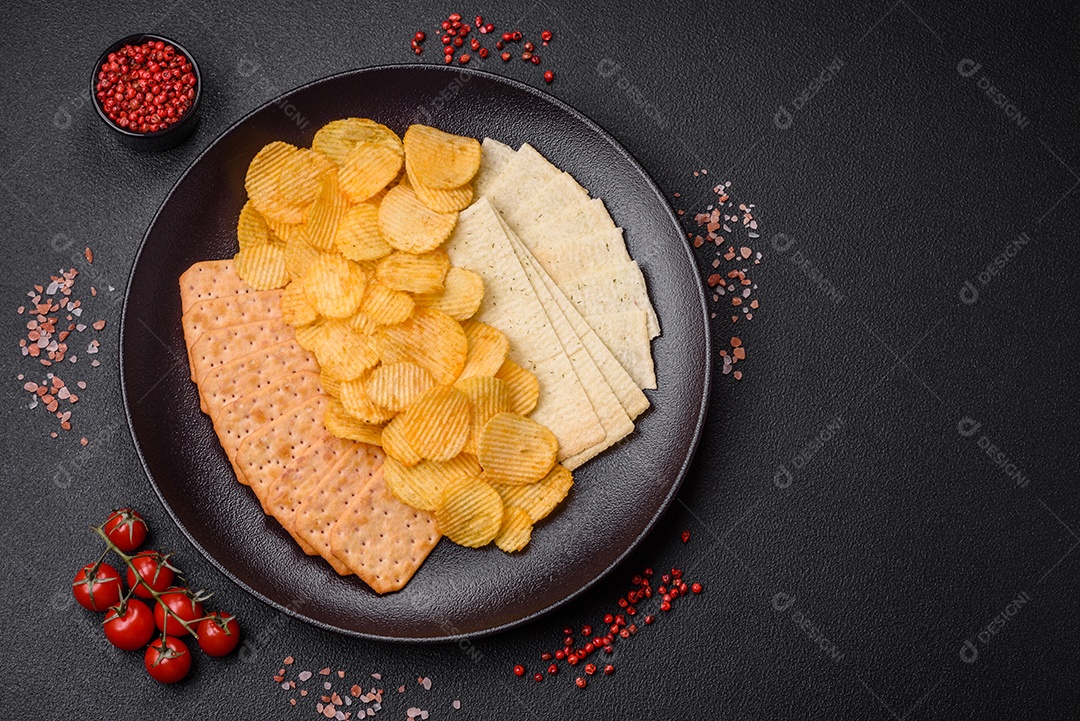 Batatas fritas crocantes com sal, especiarias e ervas sobre um fundo escuro de concreto