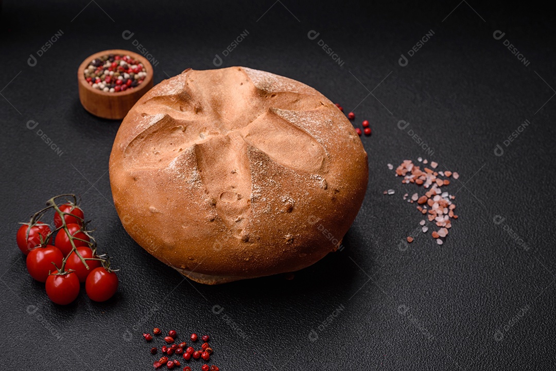 Delicioso pão redondo fresco, crocante e aromático com sementes e grãos sobre um fundo escuro de concreto