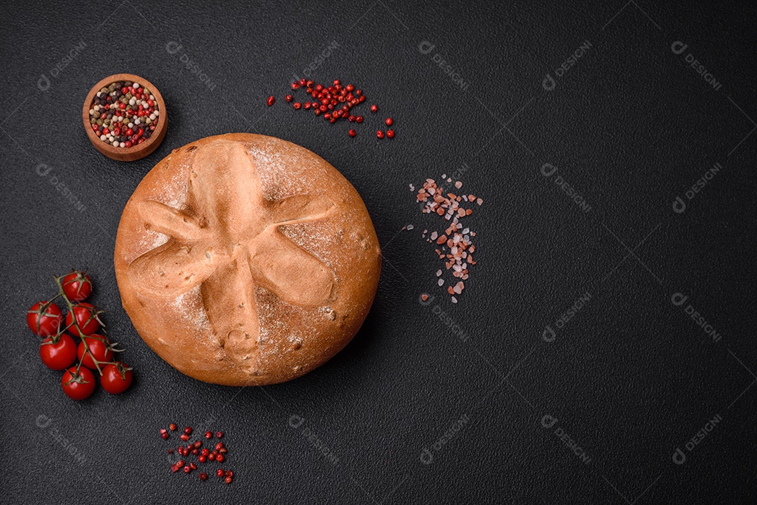 Delicioso pão redondo fresco, crocante e aromático com sementes e grãos sobre um fundo escuro de concreto