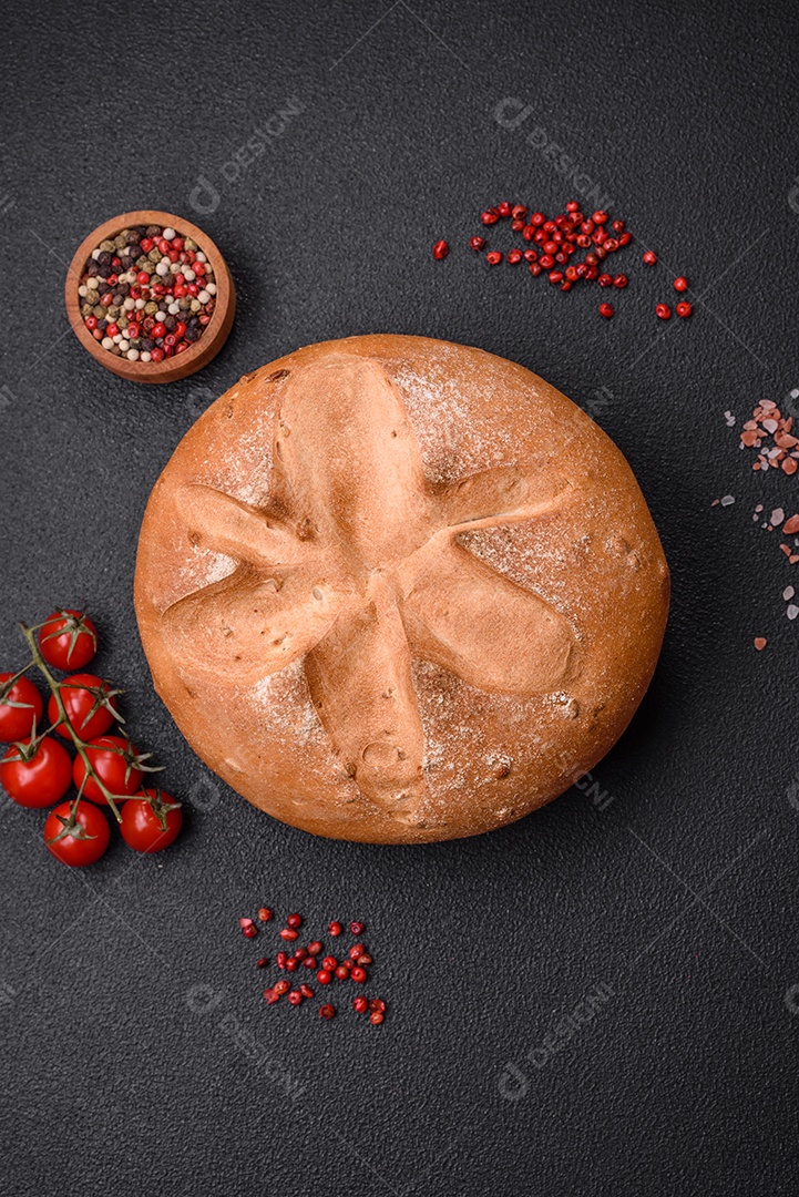 Delicioso pão redondo fresco, crocante e aromático com sementes e grãos sobre um fundo escuro de concreto