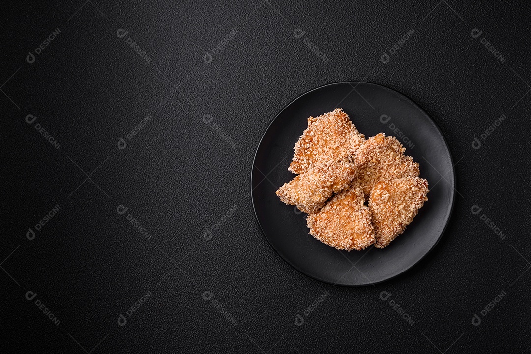 Deliciosos nuggets de frango crocantes frescos em um fundo escuro de concreto. Alimentos não saudáveis, fast food