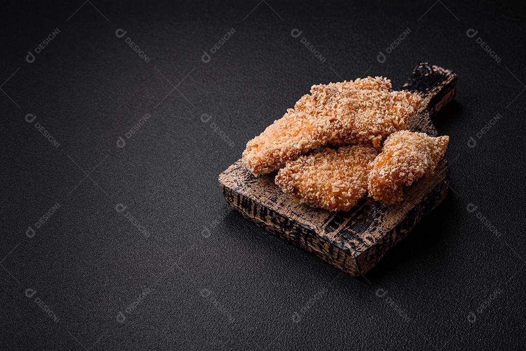 Deliciosos nuggets de frango crocantes frescos em um fundo escuro de concreto. Alimentos não saudáveis, fast food