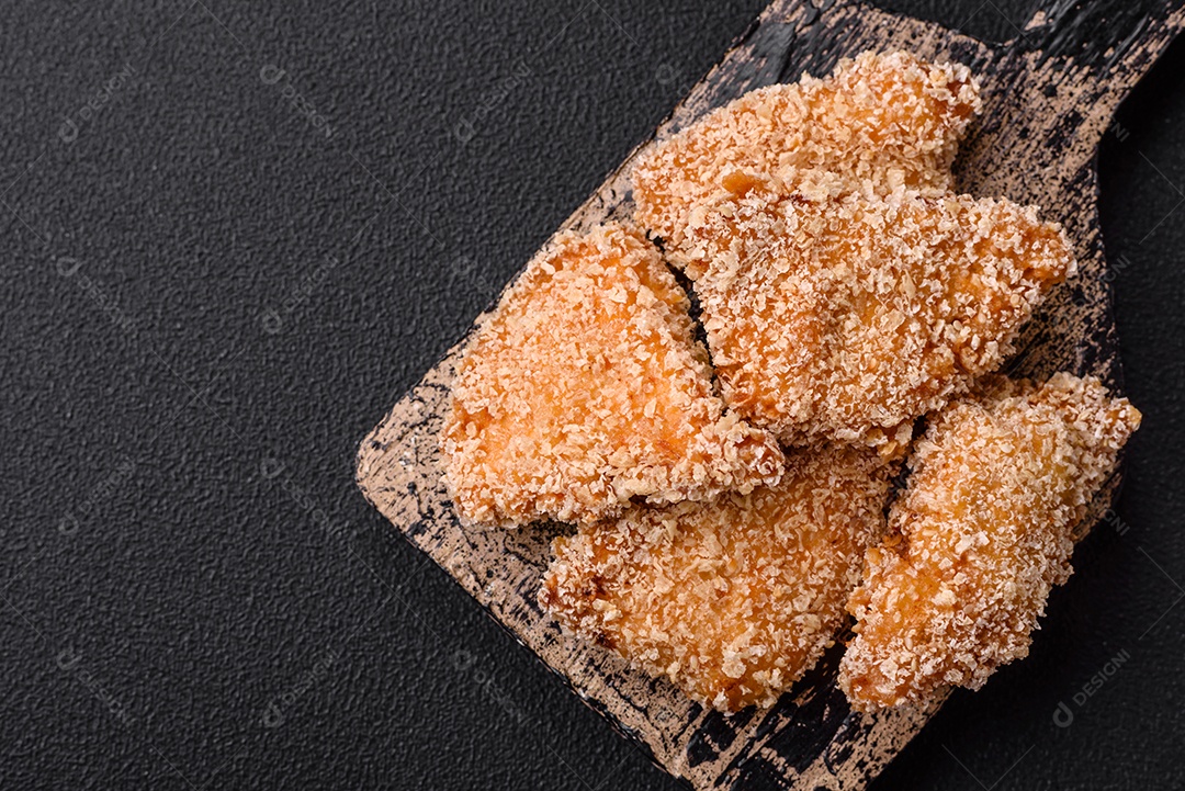 Deliciosos nuggets de frango crocantes frescos em um fundo escuro de concreto. Alimentos não saudáveis, fast food