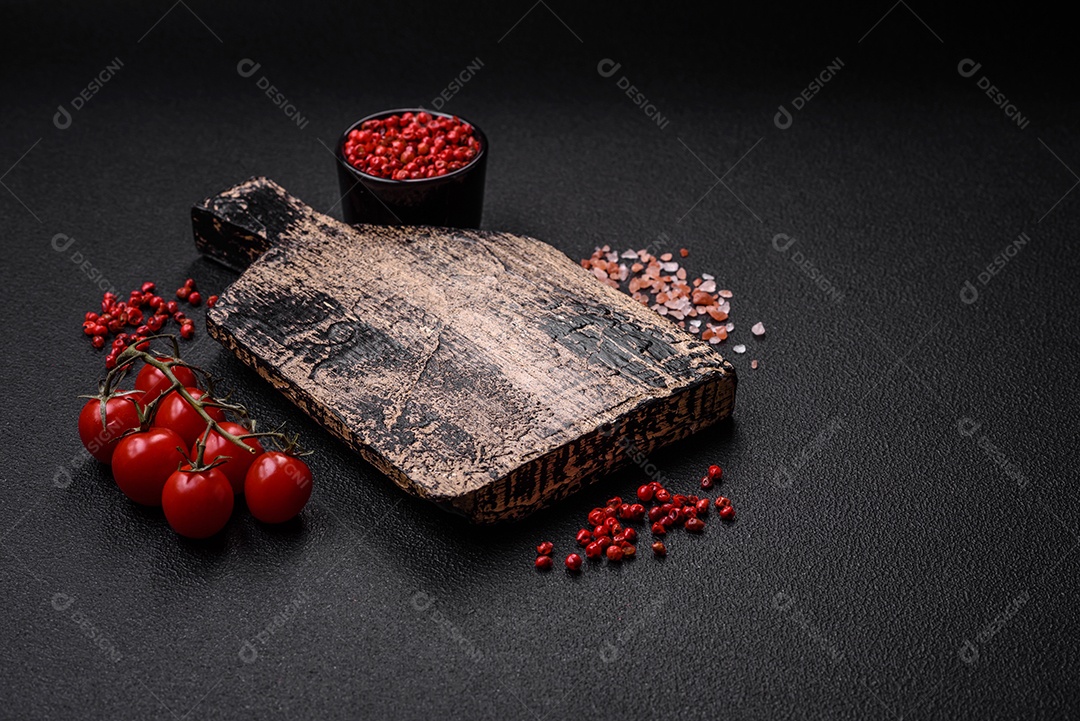 Prato vazio, tábua de madeira com sal e especiarias em fundo escuro de concreto