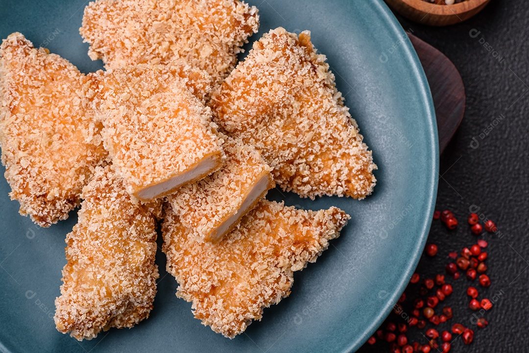 Deliciosos nuggets de frango crocantes frescos em um fundo escuro de concreto. Alimentos não saudáveis, fast food