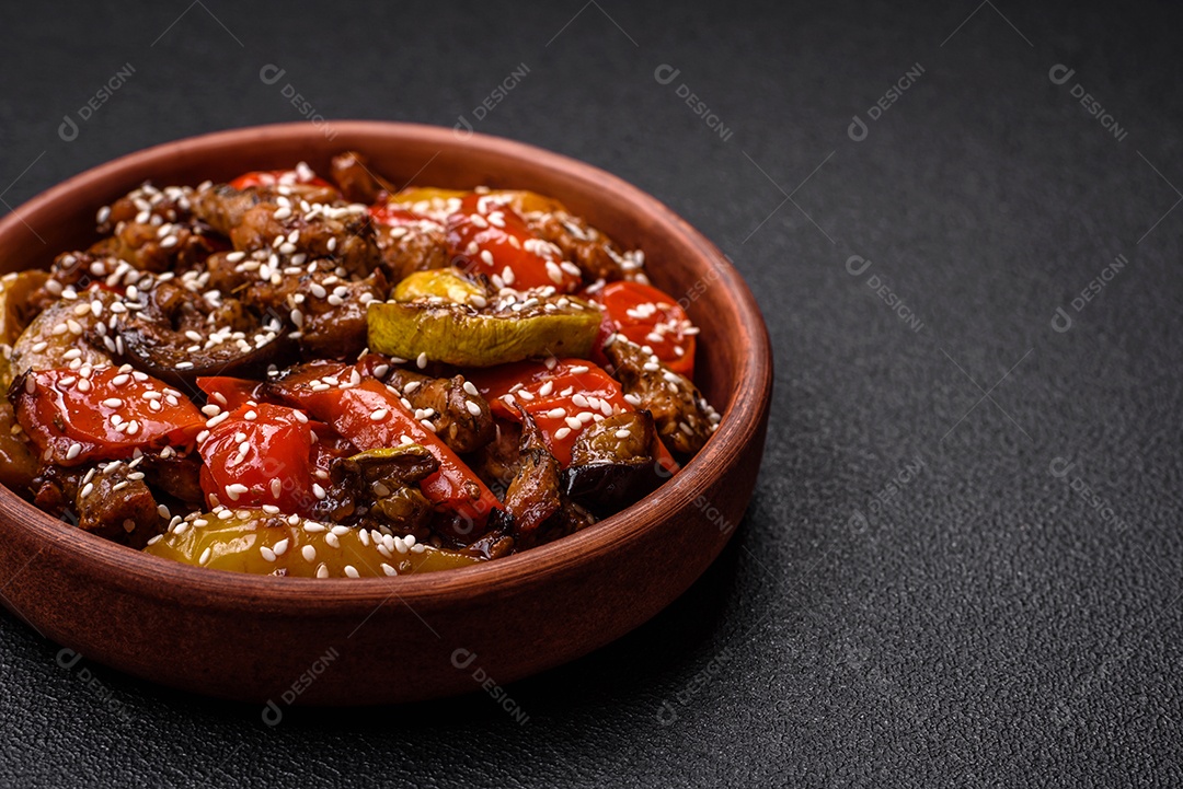 Salada quente com vitela, tomate, pimentão, abobrinha, gergelim, sal, especiarias e ervas sobre fundo escuro de concreto