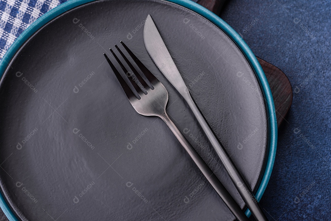 Placa cerâmica colorida vazia redonda em fundo de textura de concreto. Preparando pratos e talheres para o jantar