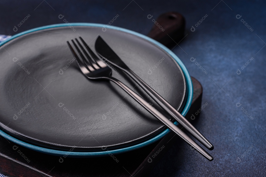 Placa cerâmica colorida vazia redonda em fundo de textura de concreto. Preparando pratos e talheres para o jantar