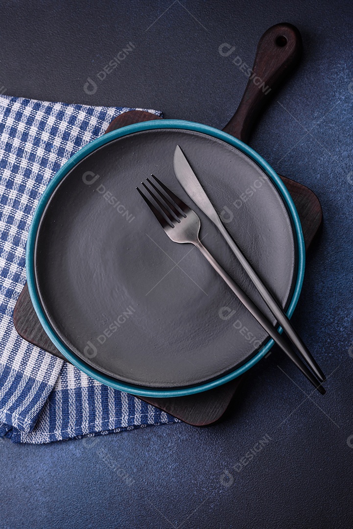 Placa cerâmica colorida vazia redonda em fundo de textura de concreto. Preparando pratos e talheres para o jantar