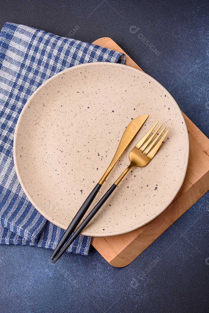 Placa cerâmica colorida vazia redonda em fundo de textura de concreto. Preparando pratos e talheres para o jantar