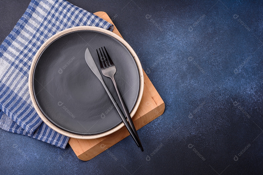 Placa cerâmica colorida vazia redonda em fundo de textura de concreto. Preparando pratos e talheres para o jantar