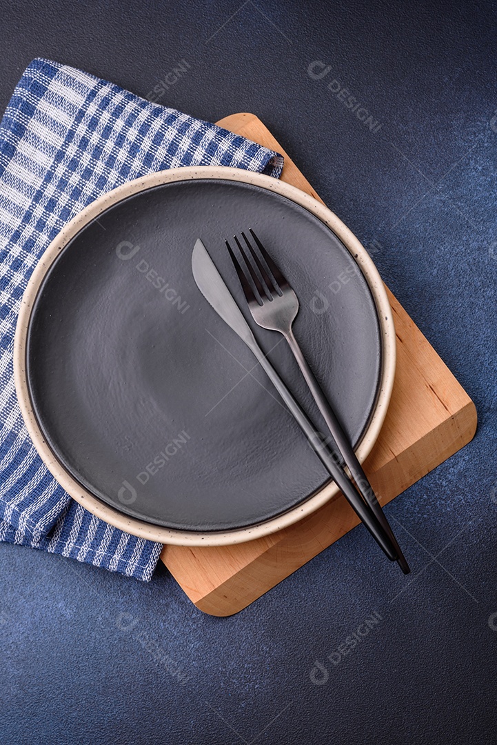 Placa cerâmica colorida vazia redonda em fundo de textura de concreto. Preparando pratos e talheres para o jantar