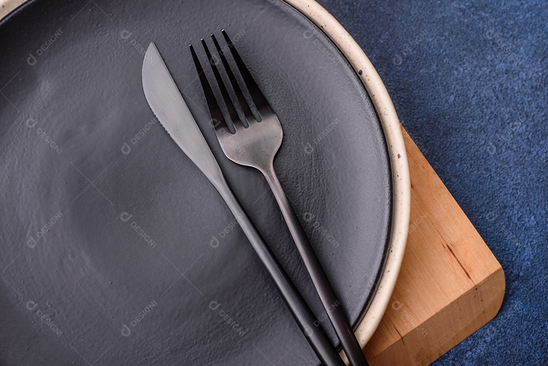 Placa cerâmica colorida vazia redonda em fundo de textura de concreto. Preparando pratos e talheres para o jantar