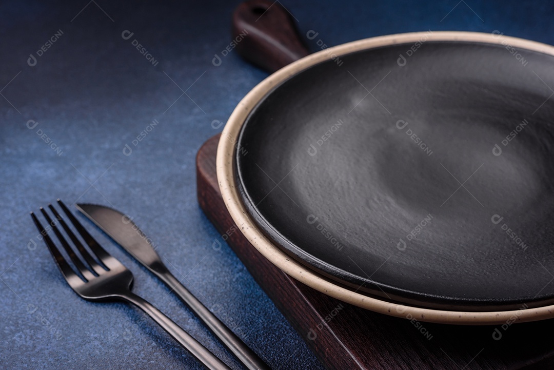 Placa cerâmica colorida vazia redonda em fundo de textura de concreto. Preparando pratos e talheres para o jantar