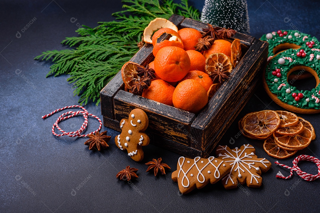 Linda composição festiva de Natal de tangerinas, pão de gengibre e anis estrelado em um fundo escuro e texturizado