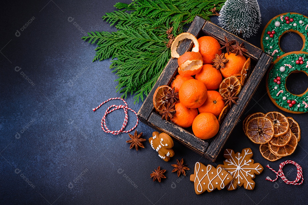 Linda composição festiva de Natal de tangerinas, pão de gengibre e anis estrelado em um fundo escuro e texturizado