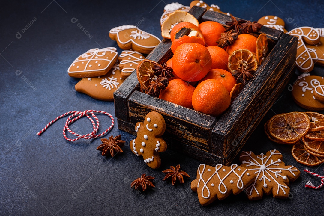 Linda composição festiva de Natal de tangerinas, pão de gengibre e anis estrelado em um fundo escuro e texturizado