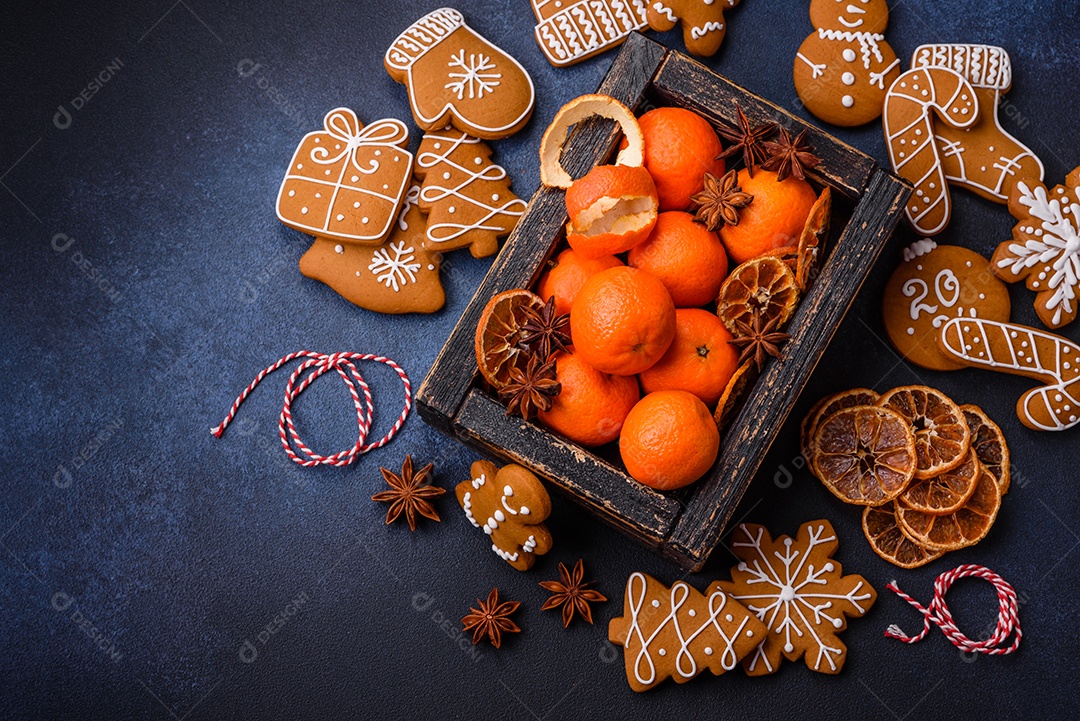 Linda composição festiva de Natal de tangerinas, pão de gengibre e anis estrelado em um fundo escuro e texturizado