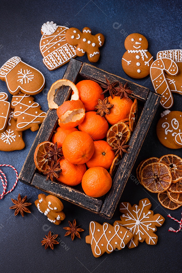 Linda composição festiva de Natal de tangerinas, pão de gengibre e anis estrelado em um fundo escuro e texturizado