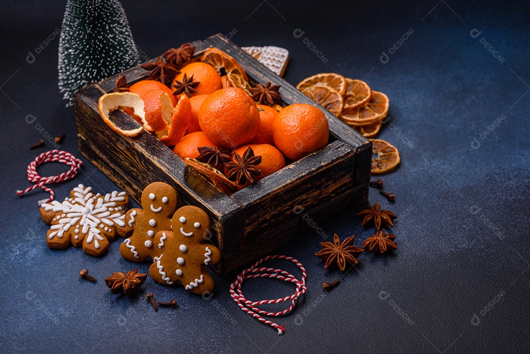 Linda composição festiva de Natal de tangerinas, pão de gengibre e anis estrelado em um fundo escuro e texturizado
