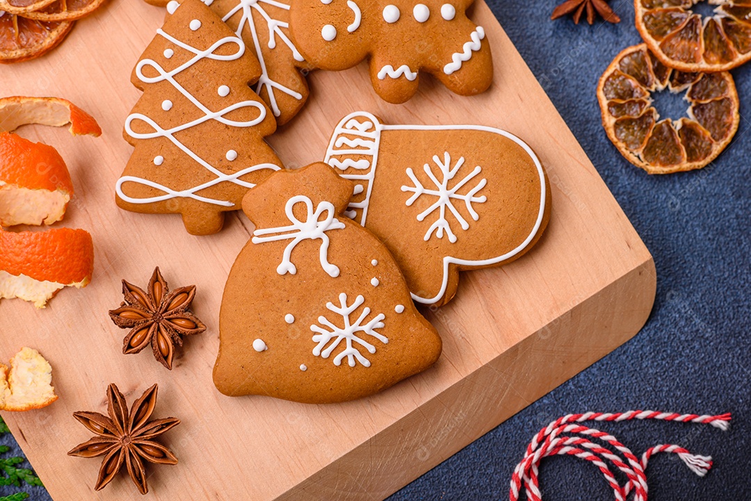 Linda composição festiva de Natal de tangerinas, pão de gengibre e anis estrelado em um fundo escuro e texturizado