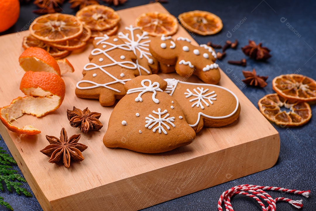 Linda composição festiva de Natal de tangerinas, pão de gengibre e anis estrelado em um fundo escuro e texturizado