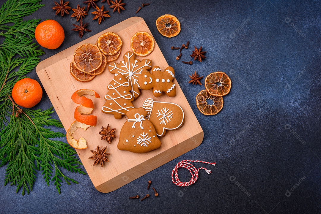 Linda composição festiva de Natal de tangerinas, pão de gengibre e anis estrelado em um fundo escuro e texturizado