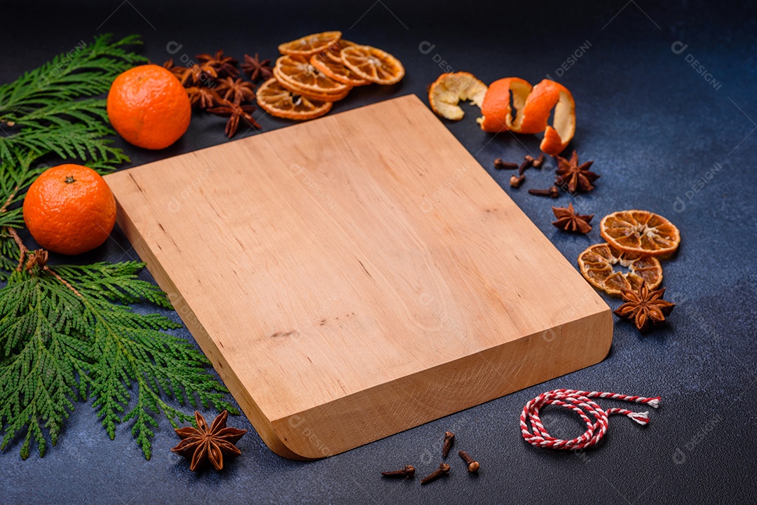 Linda composição festiva de Natal de uma tábua vazia, tangerina, pão de gengibre e anis estrelado em um fundo escuro e texturizado