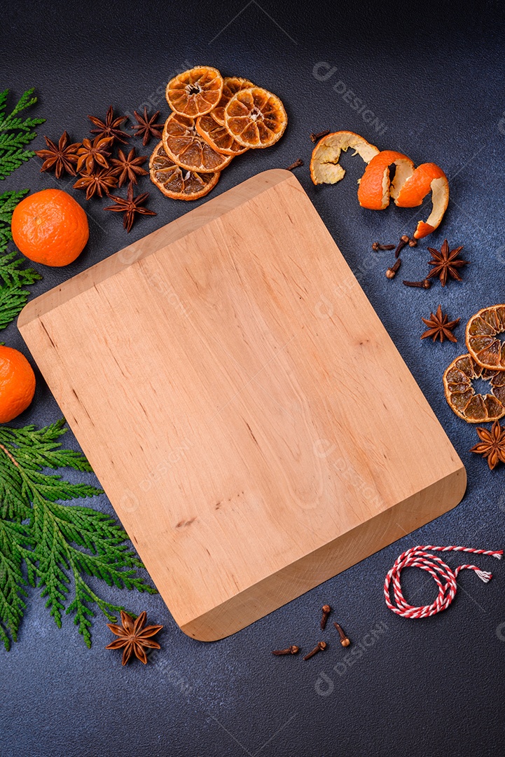 Linda composição festiva de Natal de uma tábua vazia, tangerina, pão de gengibre e anis estrelado em um fundo escuro e texturizado