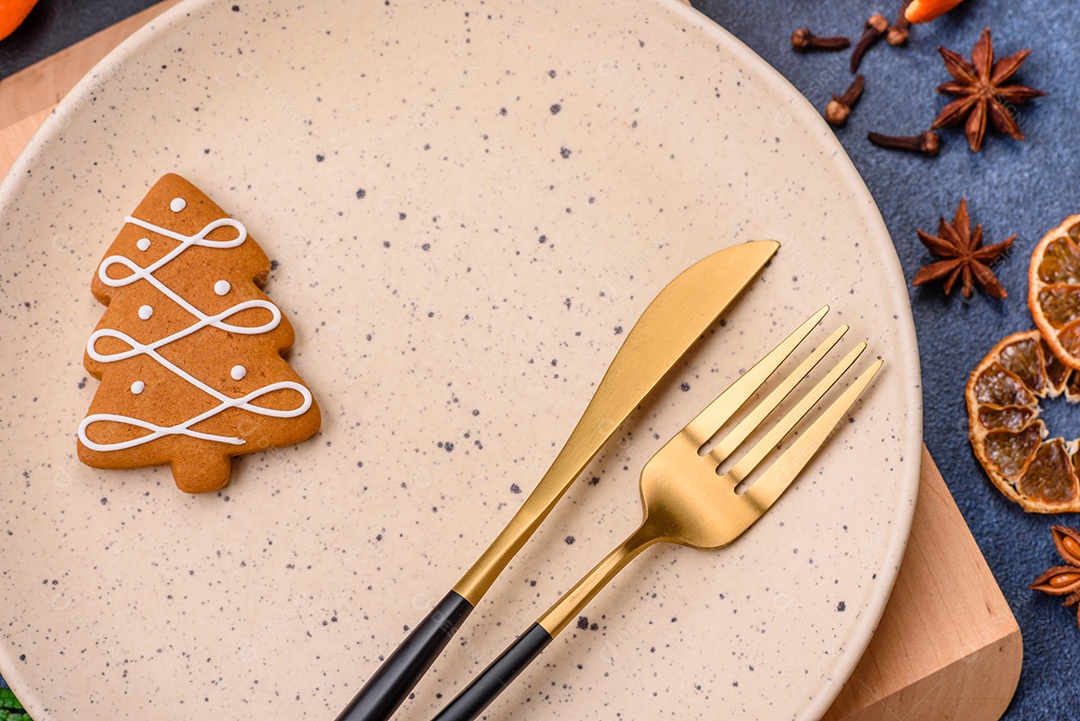 Linda composição festiva de Natal de um prato vazio, tangerina, pão de gengibre e anis estrelado em um fundo escuro e texturizado