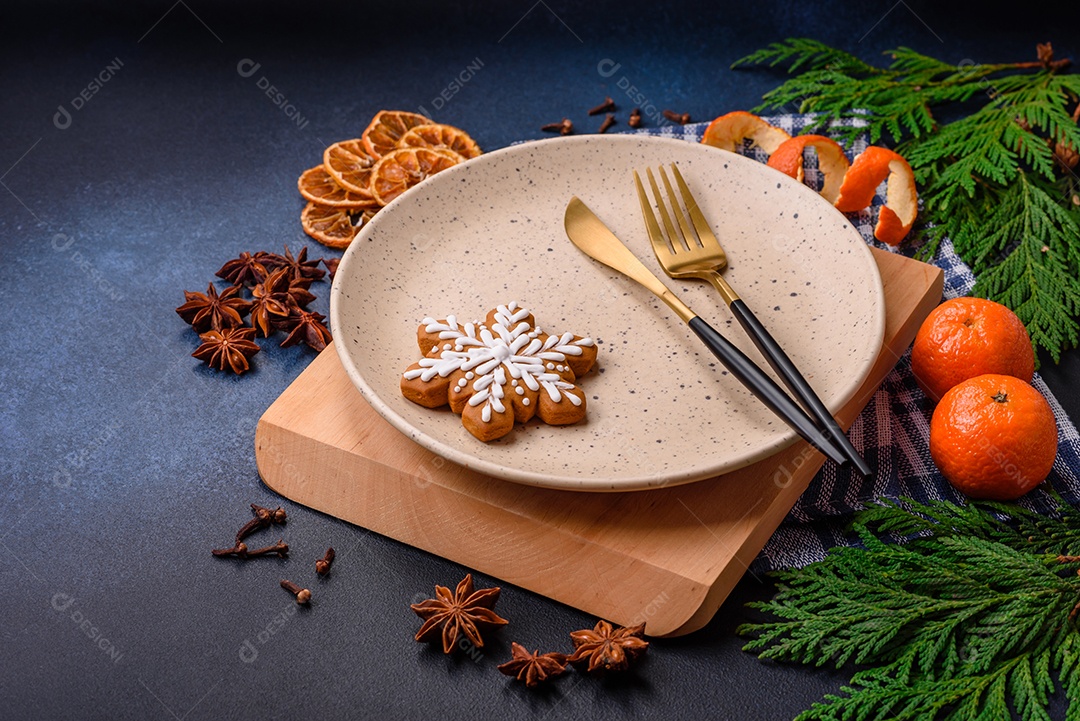 Linda composição festiva de Natal de um prato vazio, tangerina, pão de gengibre e anis estrelado em um fundo escuro e texturizado