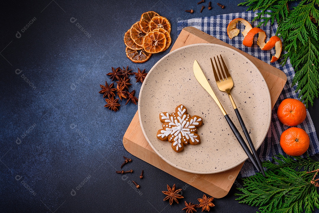 Linda composição festiva de Natal de um prato vazio, tangerina, pão de gengibre e anis estrelado em um fundo escuro e texturizado