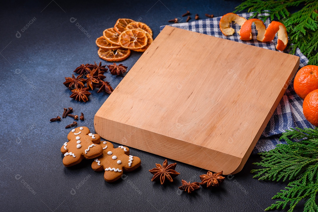 Linda composição festiva de Natal de um prato vazio, tangerina, pão de gengibre e anis estrelado em um fundo escuro e texturizado