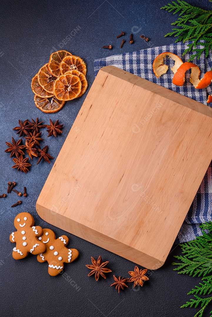 Linda composição festiva de Natal de uma tábua vazia, tangerina, pão de gengibre e anis estrelado em um fundo escuro e texturizado