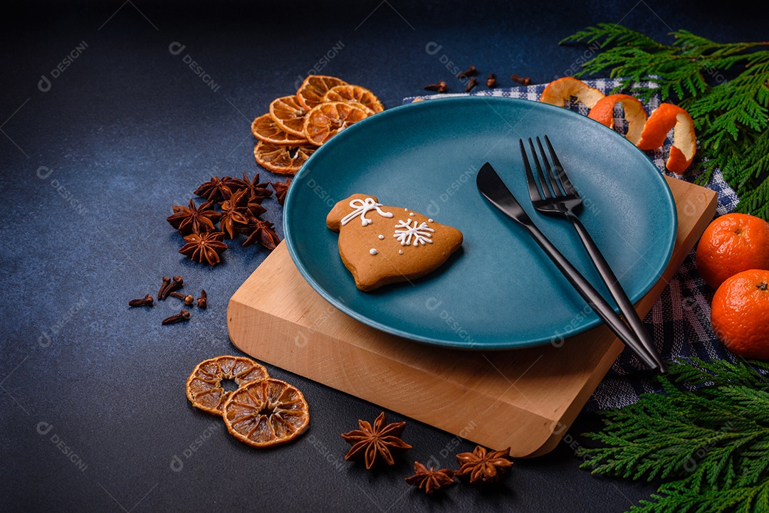 Linda composição festiva de Natal de um prato vazio, tangerina, pão de gengibre e anis estrelado em um fundo escuro e texturizado